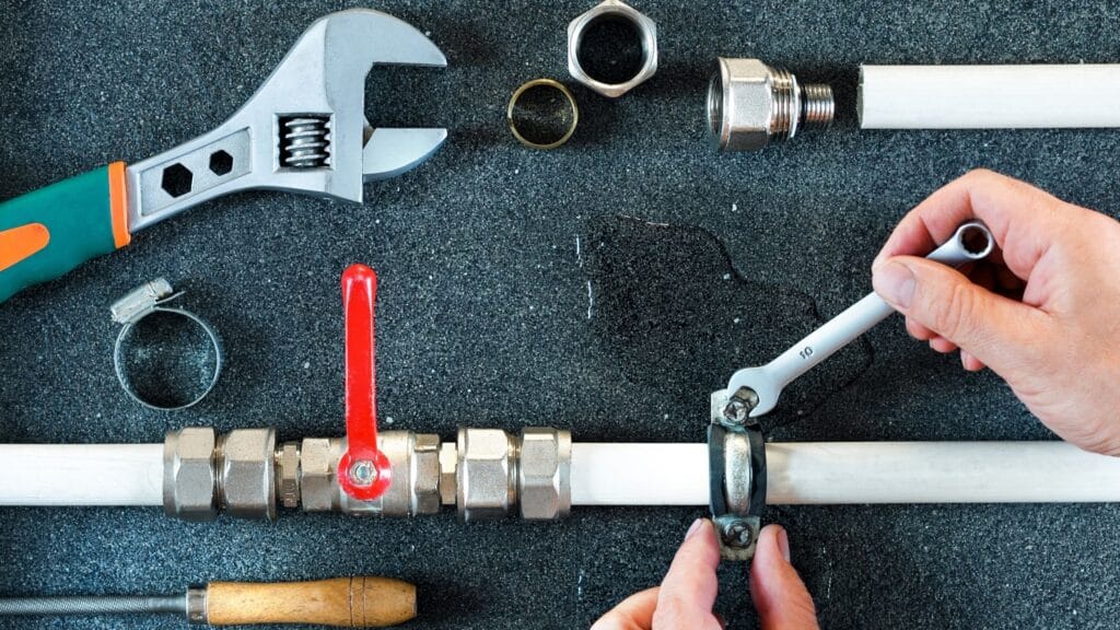 Plumber repairing a pipe valve with an adjustable wrench in Palm City