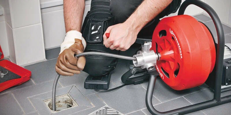 Plumber using a drain-cleaning machine in Palm City