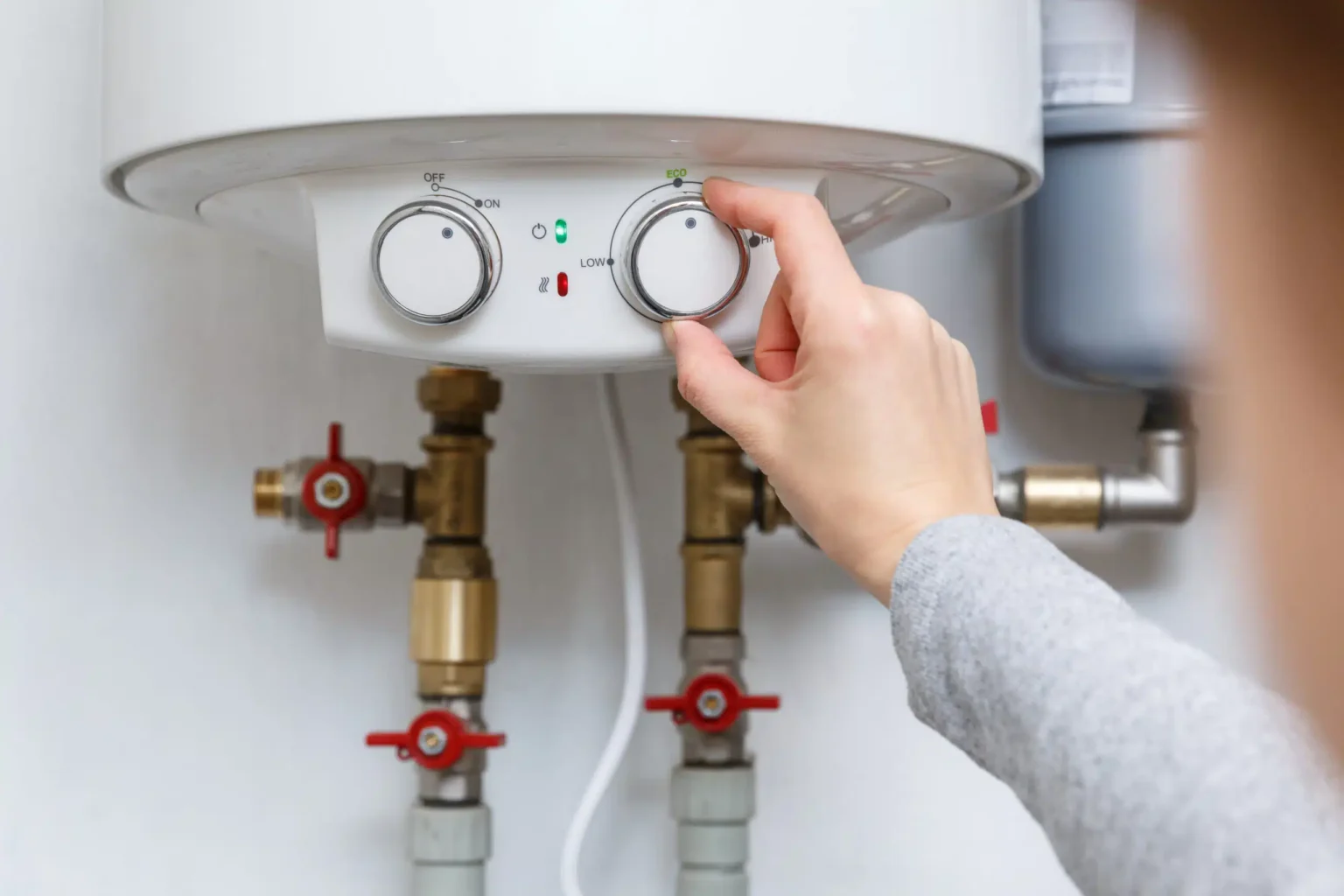 Homeowner adjusting the temperature controls on a water heater in Palm City